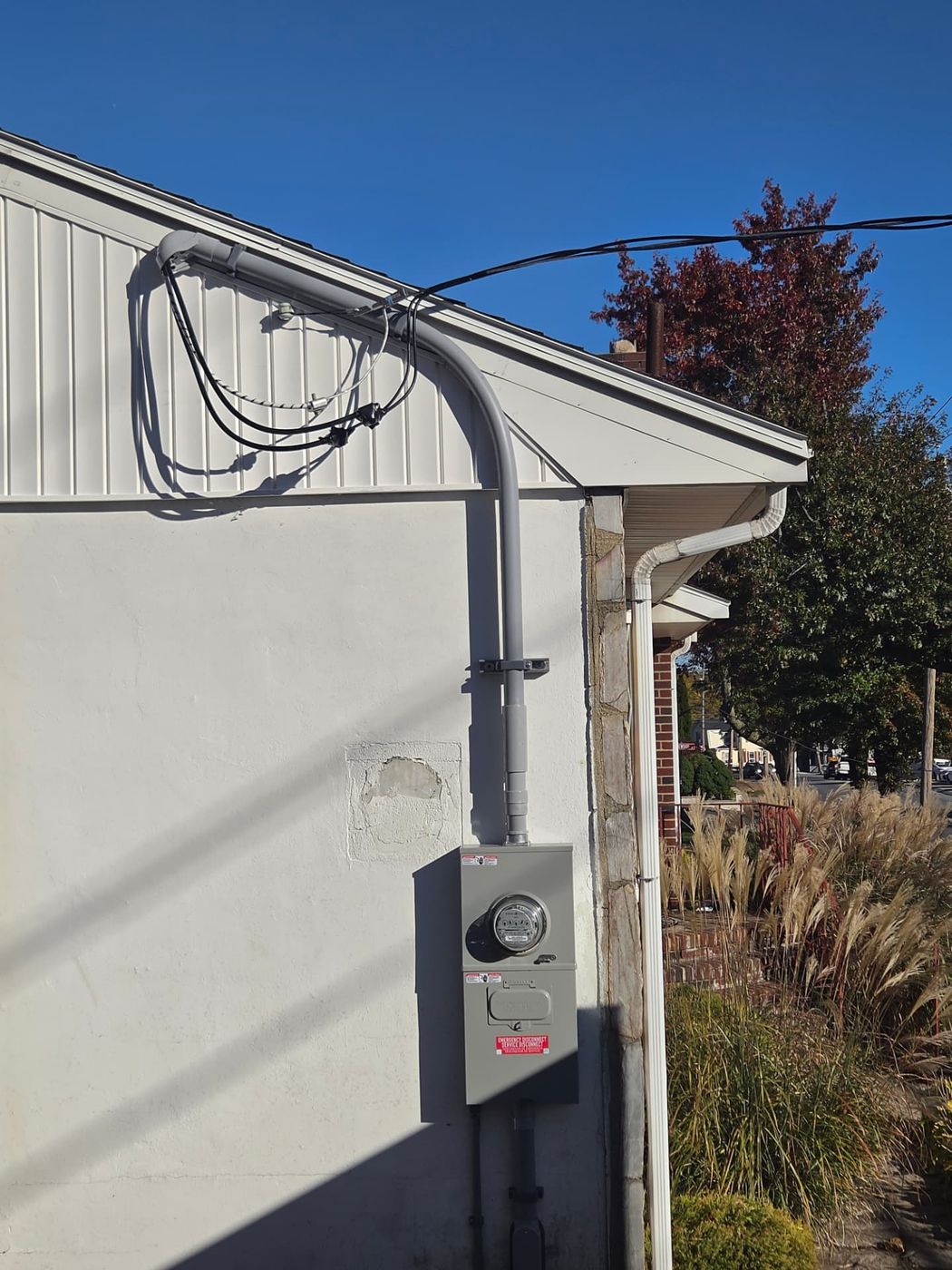 New exterior meter base and emergency disconnect mounted on the side of a home, with conduit run up the wall to the service entrance